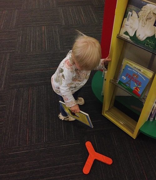 Toddler with board books in library