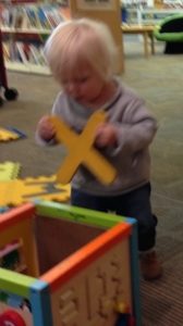 Toddler playing with letter X in Library